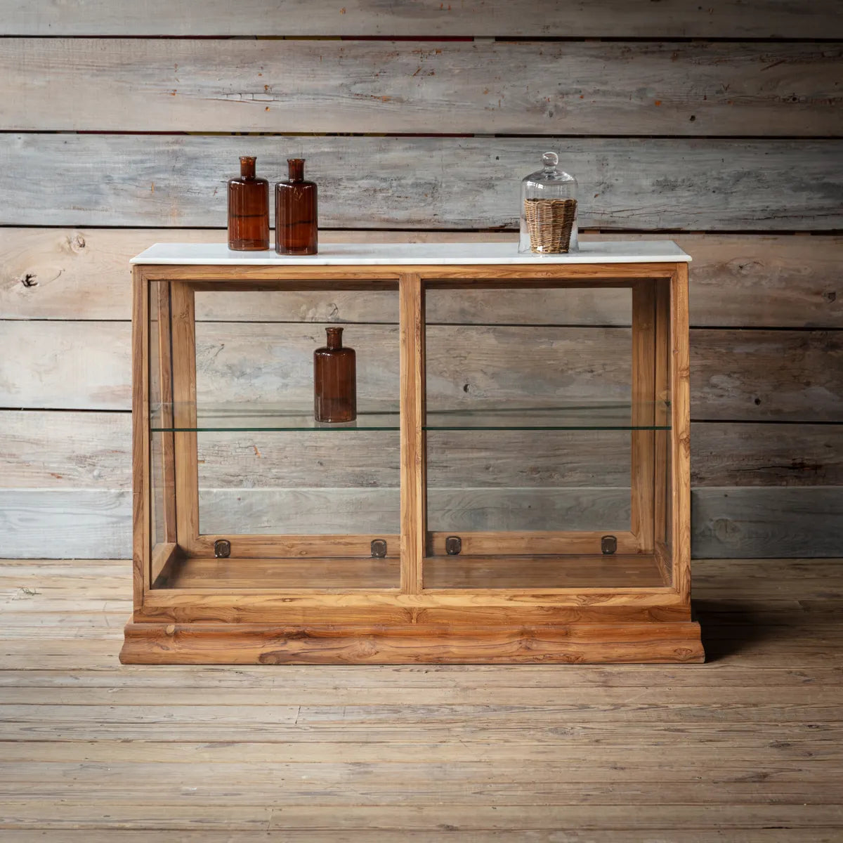 A marble top display counter with wood finish, featuring glass shelves and items displayed on top,